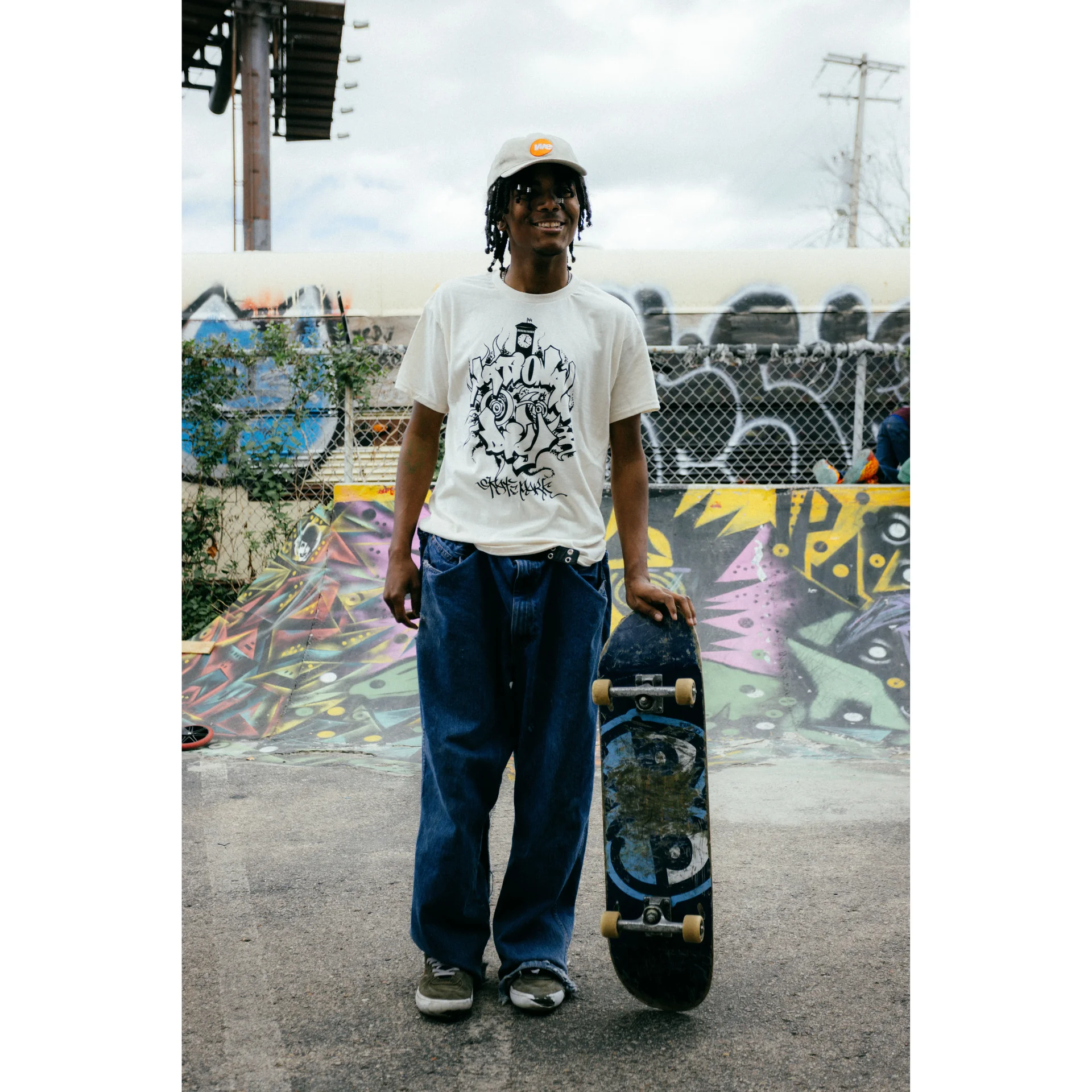 Young skater smiling holding his skateboard.